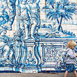 Boy walking in front of cloisters of Porto cathedral, Portugal.